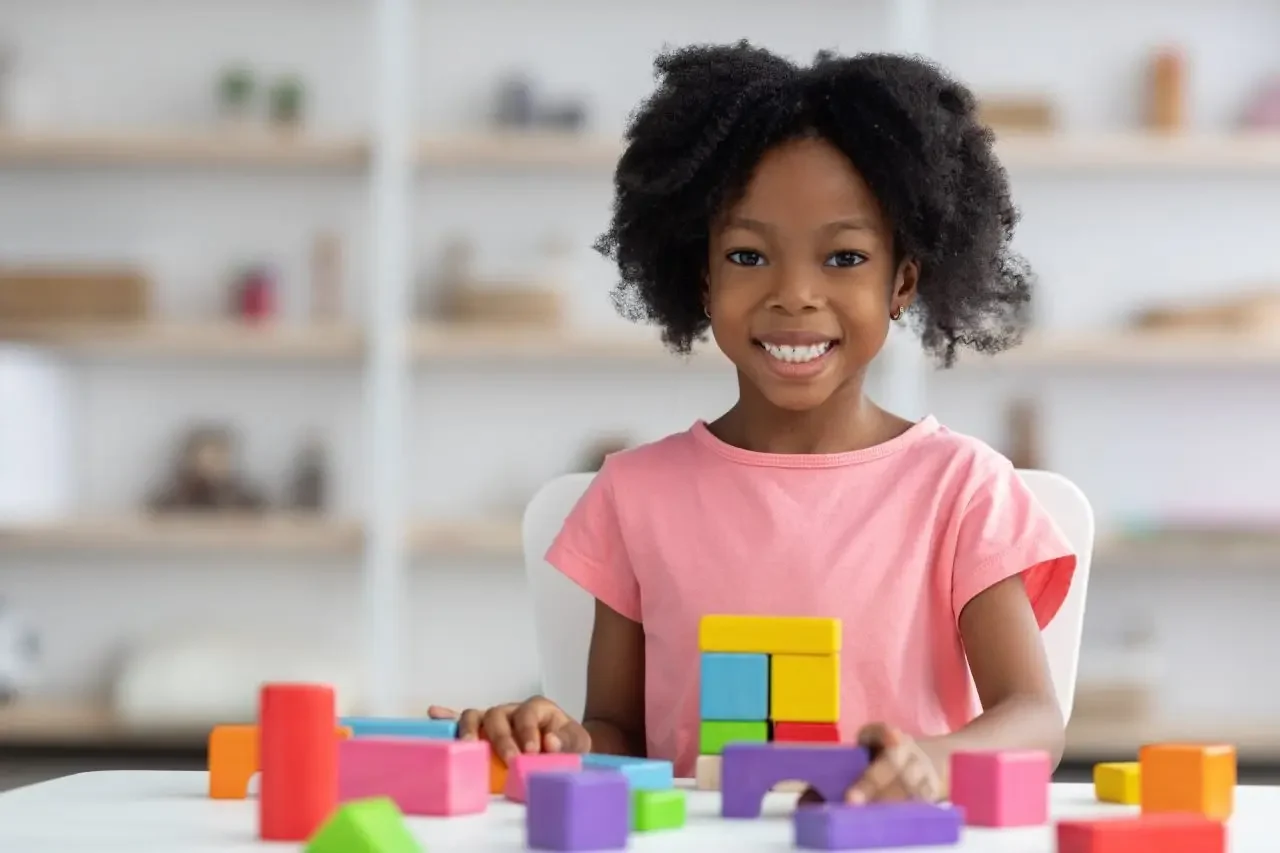 portrait of cheerful adorable kid playing with wood blocks.webp